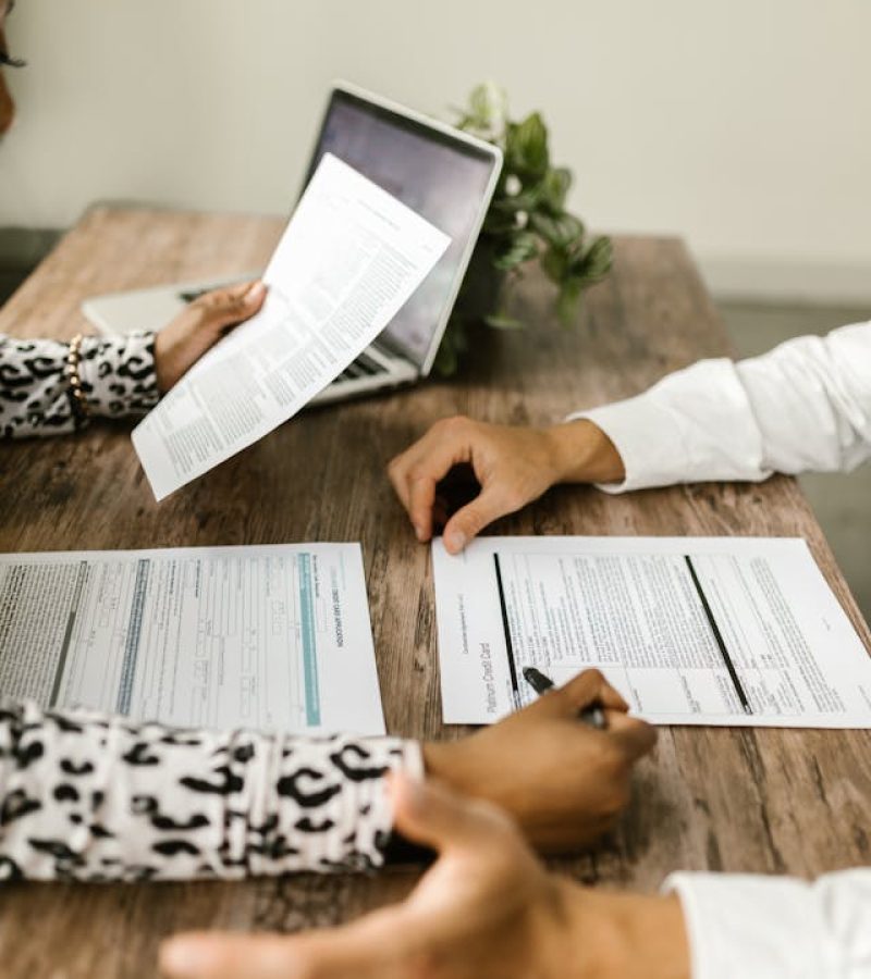 a man and a woman's hands on the table signing documents